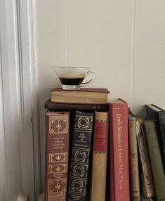 a stack of books sitting on top of a table next to a cup of coffee