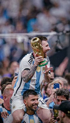 a man holding up a trophy while surrounded by other men in the crowd at a sporting event