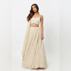 This Powder Peach Lehenga Has A Geometric Pattern Incorporated By Elegant Pearl Embroidery Work. This Lehenga Is Featured On A Net Base With Pearl Tassel Detailing On The Blouse. The Dupatta Includes An Intricate Pearl Design Pattern On A Net Fabric To Compliment The Lehenga's Embroidery Work. This Was Worn Once On My Wedding Day! I Loved It But Sadly Don’t Have Anywhere To Store It At Home. My Measurements Are In The Final Photo. Cream Dress For Navratri Reception, Fitted Sharara With Chikankari Embroidery For Reception, Elegant Navratri Choli With Chikankari Embroidery, Beige Embroidered Fabric For Reception, Off White Floor-length Sharara For Reception, Off-white Floor-length Sharara For Reception, Fitted Floor-length Cream Sharara, Floor-length Off White Sharara For Reception, Festive Beige Georgette Lehenga