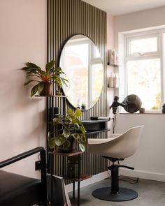 a room with a chair, mirror and potted plant on the table in front of it