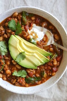 a white bowl filled with beans, avocado and sour cream sitting on top of a table