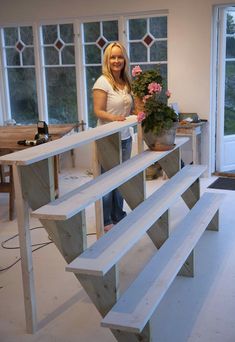 a woman standing next to a bench made out of wooden planks and plywood