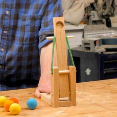 a man standing in front of a wooden easel with balls on the table next to it