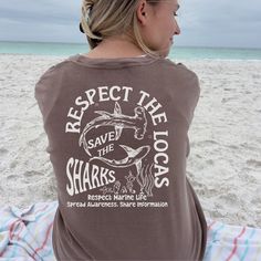 Make waves with our "Protect The Shark Save The Ocean" shirt! Designed for shark lovers and ocean enthusiasts, this trendy t-shirt features a captivating shark design and a bold conservation message. It's the perfect summer beach shirt. Surprise your favorite surfer or marine enthusiast with this thoughtful and trendy gift. It's a reminder that we can all make a difference in saving our oceans, one stylish hoodie at a time. Comfort Colors C1717 Shirts - Shirt sizes are unisex, please refer to si Graphic Tee With Shark Design And Crew Neck, Save The Ocean, Ocean Shirt, Shark Design, Save Our Oceans, Shark Lover, Hammerhead Shark, Surf Tshirt, Ocean Conservation