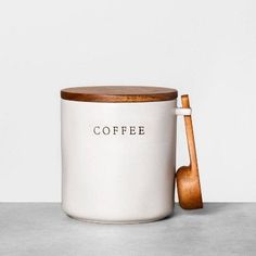 a white coffee mug with a wooden spoon in front of it and the word coffee written on the side