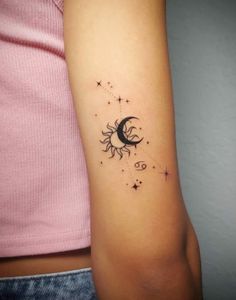 a woman's arm with a small sun and moon tattoo on the left side