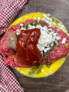 a plate filled with meat, onions and ketchup on top of a wooden table