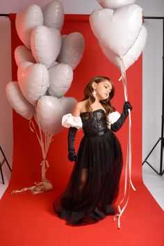 a woman in a black dress holding white balloons