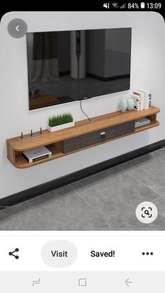 a flat screen tv sitting on top of a wooden shelf next to a white wall