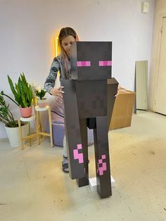 a woman standing next to a gray cat made out of paper and pink pixeles