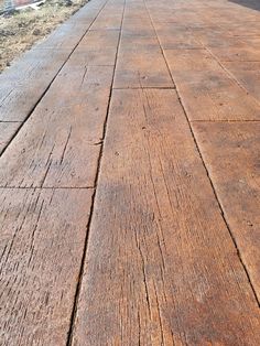 an old wooden bench sitting on the side of a road next to a building and grass