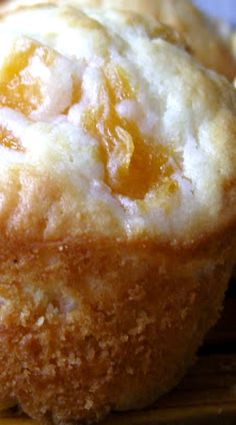 a close up of a muffin on a wooden surface with other muffins in the background