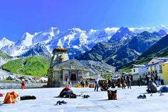 many people are sitting on the ground in front of some snow covered mountains and buildings