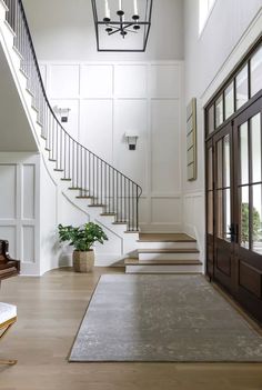 an elegant entryway with stairs leading up to the second floor and potted plant on the far side