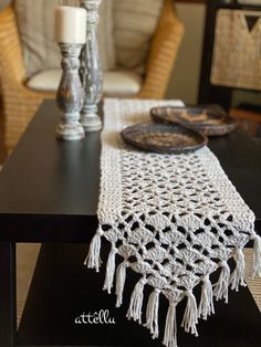 a crocheted table runner sitting on top of a wooden table next to a candle