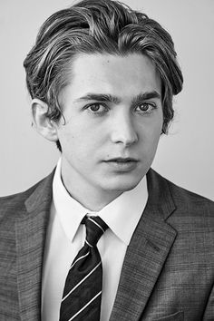 a young man in a suit and tie poses for a black and white photo with his eyes wide open