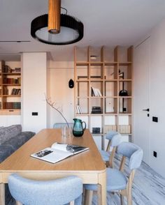 a dining room table with blue chairs and bookshelves