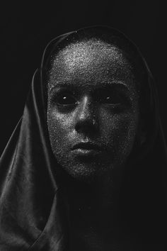 a black and white photo of a woman's face covered in silver glitters