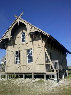 an old wooden building sitting on top of a lush green field