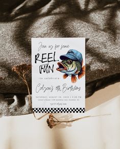 a birthday card with a fish on it sitting on top of a bed next to a t - shirt