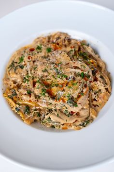 a white plate topped with pasta covered in sauce and parsley on top of it