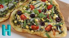 two pizzas with toppings sit on a cutting board