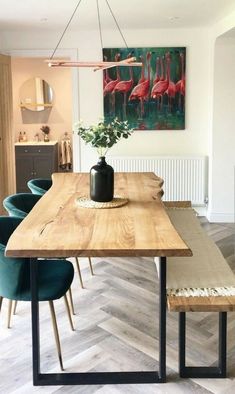 a wooden table with blue chairs and a painting on the wall