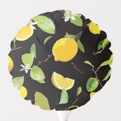 a black paper plate with lemons and leaves on it, against a white background