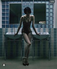 a woman in a bathing suit is sitting on a stool next to a bathroom sink