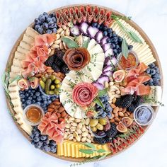 a platter filled with different types of cheeses and fruits on top of a marble table