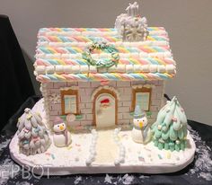 this is a cake that looks like a house with snowmen and trees on it