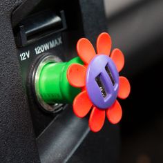 an orange and purple flower sitting on top of a green button next to a black machine