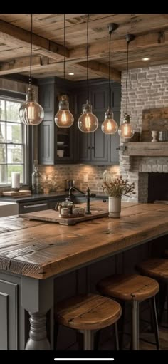 a kitchen island with stools and lights hanging from it