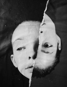 a black and white photo of a child's face through a torn piece of paper