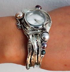 From Porans Watches collection: Unique silver cuff watch with a white, black, and cream Pearls inlaid. Dimensions:  Max front Width: 39 mm\ 1.56 inches. Back width: 10 mm\ 0.39 inches.  Our watch is top quality stainless still, analog, Japanese movement with water resistance (up to 3 atmospheres) and it is powered by a battery that lasts about 3 years. The battery can be exchanged. Please notice that because the watch is made to order the watch mechanism part may look different than the picture, Handmade Elegant Formal Watches, Elegant Handmade Formal Watches, Watch Mechanism, Watches Collection, Womens Cuff Bracelets, Unique Women, Wide Cuff Bracelets, Cuff Watch, Pearl Cream