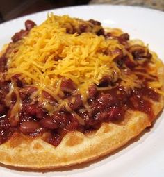 a waffle topped with chili and cheese on a white plate