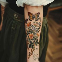 a woman with a butterfly tattoo on her arm and wrist is holding a flower bouquet