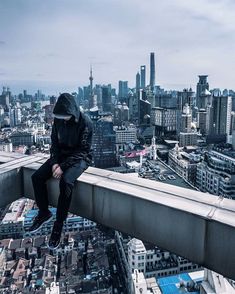 a man sitting on the edge of a high building looking down at a cityscape