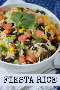 a white bowl filled with rice and beans on top of a blue table cloth next to a fork