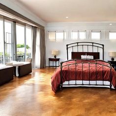 a bedroom with hardwood floors and white walls, has a large bed in the center