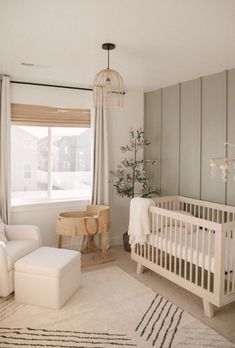 a baby's room with a white crib, chair and ottoman in it