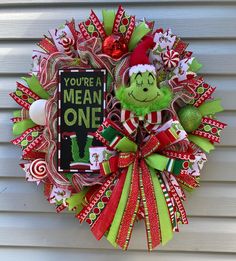 a christmas wreath on the front door with a griny face and candy canes