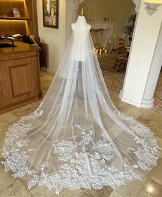 a white wedding veil is on display in a room with a fireplace and chandelier