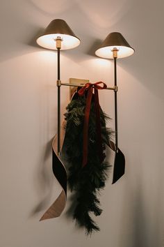 a couple of lights hanging from the side of a wall next to a christmas wreath