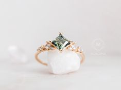 a green diamond ring sitting on top of a white rock