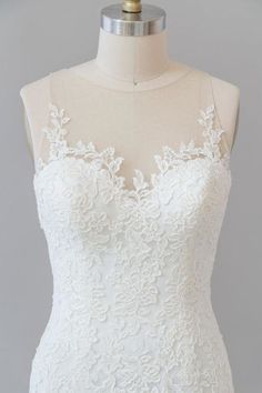 a white wedding dress on a mannequin with an open back and lace detailing