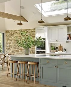 a kitchen with two stools next to an island in front of a brick wall