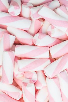 pink and white candy canes are piled on top of each other