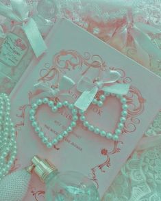 an open book with pearls and a necklace on top of it next to a bottle of perfume