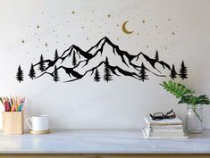 a wall decal with mountains and stars in the night sky, on top of a table